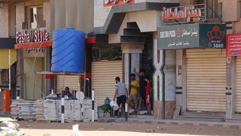 epa10579978 Sudanese people stand in front of a shop in Khartoum, Sudan, 19 April 2023. A power struggle erupted since 15 April between the Sudanese army led by army Chief General Abdel Fattah al-Burhan and the paramilitaries of the Rapid Support Forces (RSF) led by General Mohamed Hamdan Dagalo, resulting in at least 200 deaths according to doctors' association in Sudan.  EPA/STRINGER