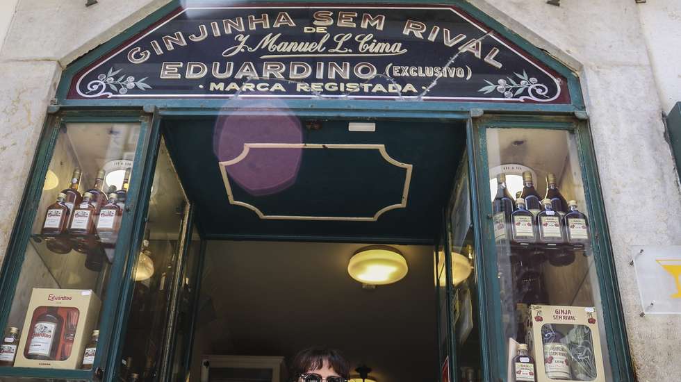 Uma turista turca posa para a fotografia com uma garrafa de ginjinha na porta de entrada da histórica loja "Ginjinha sem Rival", nas Portas de Santo Antão, em Lisboa, 25 de junho de 2025. A histórica loja Ginjinha Sem Rival, instalada na zona histórica de Lisboa desde 1890, tem ordem para encerrar portas já no final deste mês, mas o gerente promete “lutar até ao fim”, nem que seja nos tribunais. (ACOMPANHA TEXTO DA LUSA DA LUSA DO DIA 27 DE JUNHO DE 2025). TIAGO PETINGA/LUSA