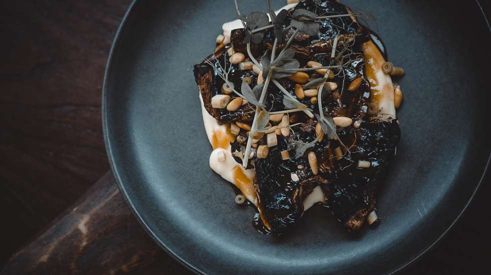Portobello braseado com glacê de cebola, puré de aipo bola, pinhão e lima caviar