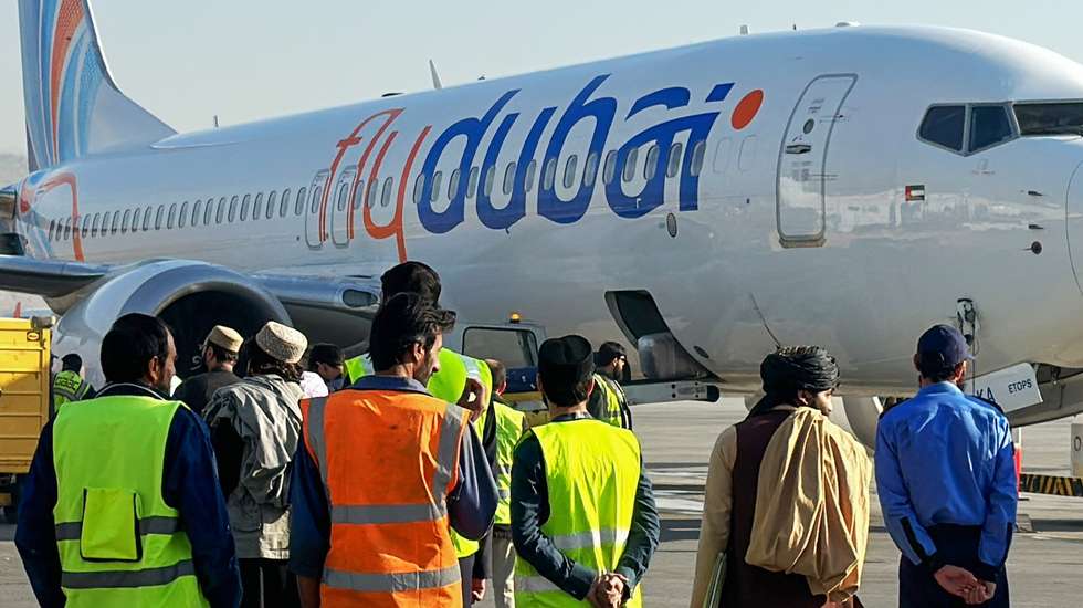 epa10976247 People stand next to a flydubai plane after it landed at Kabul airport in Kabul, Afghanistan, 15 November 2023. Flydubai resumed flights to Kabul International Airport after a two-year suspension, following the airline's October announcement to reinstate flights between the UAE and Kabul, signaling a positive step in restoring air connectivity.  EPA/SAMIULLHA POPALZAI