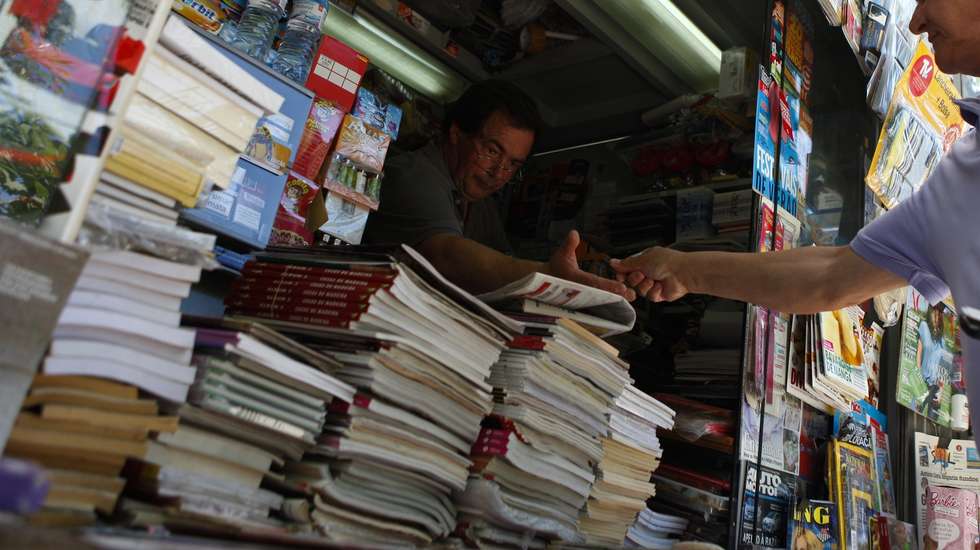 Um popular compra os jornais num quiosque de venda de revistas e jornais, em Lisboa, 13 de julho de 2013. Nos últimos anos, na Avenida da Liberdade, em miradouros pelas sete colinas, nos jardins, à beira Tejo, nas praças, os quiosques foram nascendo ou ganhando vida “como cogumelos” e, reinventando um centenário hábito lisboeta, puseram a cidade a mexer. (ACOMPANHA TEXTO). MIGUEL A. LOPES / LUSA