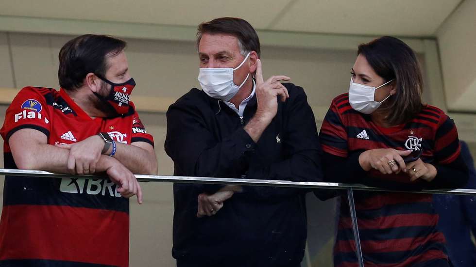 epa09357327 Brazilian President Jair Bolsonaro (C) and his wife Michelle (R) attend the Copa Libertadores soccer match between Flamengo and Defensa y Justicia at Mane Garrincha Stadium in Brasilia, Brazil, 21 July 2021.  EPA/ADRIANO MACHADO / POOL
