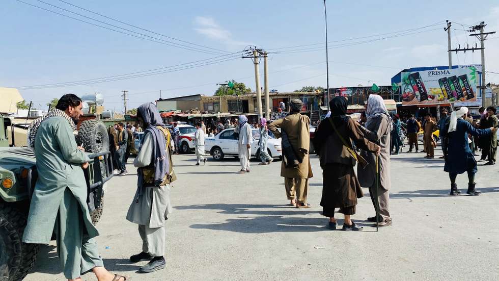 epa09421845 Taliban fighters stand guard as Afghans gather outside the Hamid Karzai International Airport to flee the country, in Kabul, Afghanistan, 20 August 2021. The Afghan interim council, formed to assist in the power transfer following President Ashraf Ghani's escape, has met several Taliban leaders to discuss issues related to control and security during the transition process. Fighting and violence have significantly reduced in Afghanistan with the surrender of the government troops and the resounding victory of the Taliban.  EPA/STRINGER