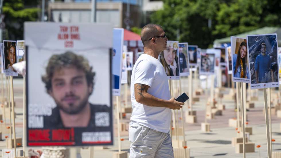epa11422549 A person looks at portraits of Israeli hostages kidnapped by Hamas militants during the October 7 attacks that are installed in front of the United Nations European headquarters in Geneva, Switzerland, 19 June 2024, during the 56th session of the Human Rights Council.  EPA/MARTIAL TREZZINI