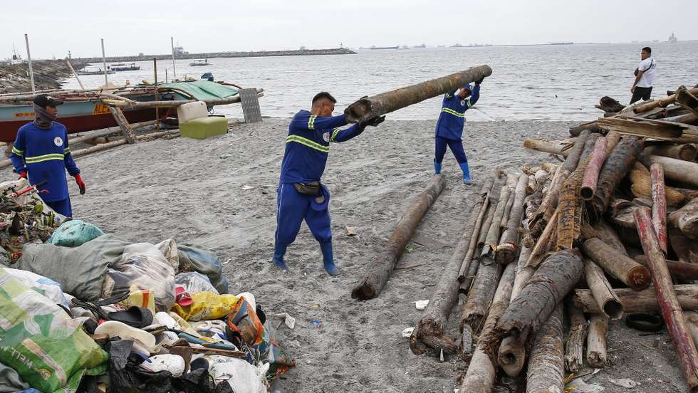 epa11725302 City maintenance workers carry a log washed to shore as they clear debris along Manila Bay in anticipation of Typhoon Man-Yi in Manila, Philippines, 17 November 2024. The Philippines' weather bureau said that typhoon Man-Yi made landfall in Aurora province of the country's Luzon region, dumping rain and sustaining winds of 185 kilometers per hour. Local government units in the typhoon's path from Bicol region to Luzon region conducted pre-emptive evacuation of citizens to safeguard against floods and strong winds.  EPA/ROLEX DELA PENA