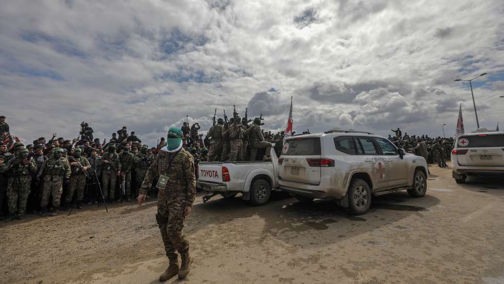 epa11915752 Armed fighters from Hamas' Izz ad-Din al-Qassam Brigades stand guard during the handover of three Israeli hostages to Red Cross representatives in Al Nuseirat refugee camp, central Gaza Strip, 22 February 2025. Six Israeli hostages were released on 22 February -- three in Nuseirat, two in Rafah and one in Gaza City -- after Hamas handed them over to the Red Cross in Gaza as part of the first phase of the Israel-Hamas ceasefire deal.  EPA/MOHAMMED SABER