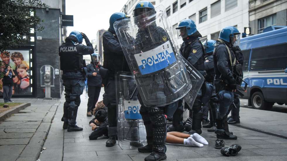 epa13314005 Italian police officers in riot gear stand around a person lying on the pavement during unrest near Piazza del Duomo in Milan, Italy, 18 October 2026. Clashes between protesters and police broke out during a demonstration against the rising cost of living on 17 October, followed by further disturbances in the city center on 18 October.  EPA/MATTEO CORNER