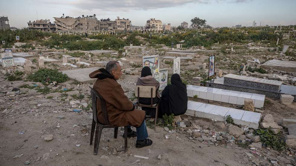 epa12836163 Palestinians sit near the graves of relatives killed during the war at the Old Gaza City cemetery during Eid al-Fitr in Gaza City, 20 March 2026. Eid al-Fitr is a three-day festival celebrated by Muslims worldwide at the end of Ramadan and is one of the two major holidays in the Islamic calendar.  EPA/MOHAMMED SABER