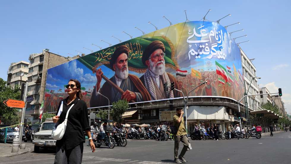 epa13027709 Iranians walk past a large billboard featuring late Iranian Supreme Leader Ayatollah Ruhollah Khomeini and Supreme Leader Ayatollah Ali Khamenei on a street in Tehran, Iran, 10 June 2026. According to US Central Command (CENTCOM), self-defense strikes were carried out against Iran near the Strait of Hormuz on 09 June in response to the downing of a US Army Apache helicopter.  EPA/ABEDIN TAHERKENAREH RESTRICTIONS: NO Access Israel Media/Persian Language TV Stations Outside Iran/Strictly No Access BBC Persian/VOA Persian/Manoto TV/Iran International TV. (As mandated by Iran's Directorate General for Foreign Media) --