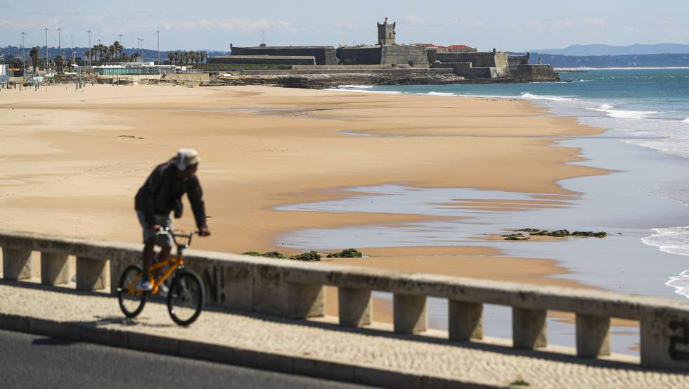 Um homem anda de bicicleta, na Avenida Marginal ao lado da Praia de Carcavelos, que se encontra vedada ao acesso do público (assim como todas as praias na zona de Cascais), em Cascais, 28 de março de 2020. Portugal regista hoje 100 mortes associadas à covid-19, mais 24 do que na sexta-feira, enquanto o número de infetados subiu 902, para 5.170, segundo o boletim epidemiológico da Direção-Geral da Saúde (DGS). ACOMPANHA TEXTO DO DIA 28 DE MARÇO DE 2020. JOSÉ SENA GOULÃO/LUSA