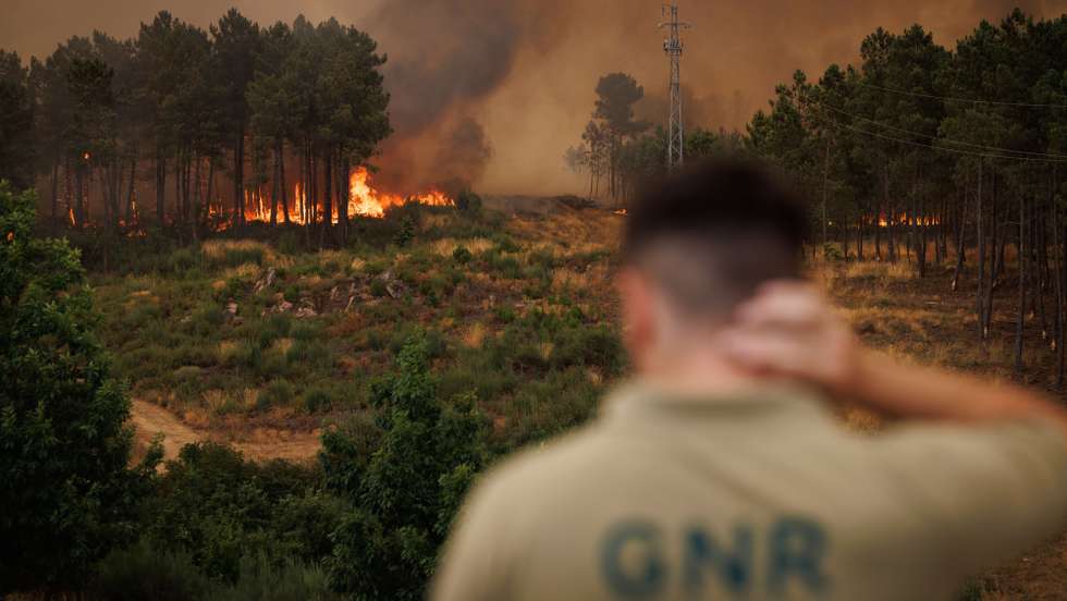 Um agente da GNR observa as chamas durante um incêndio em São Martinho da Anta, concelho de Sabrosa, Vila Real, 2 de agosto de 2025. O fogo que começou em São Cibrão, Vila Real, alastrou para o concelho de Sabrosa, onde lavra em duas frentes com alguma intensidade e mobiliza cerca de 240 operacionais. PEDRO SARMENTO COSTA/LUSA