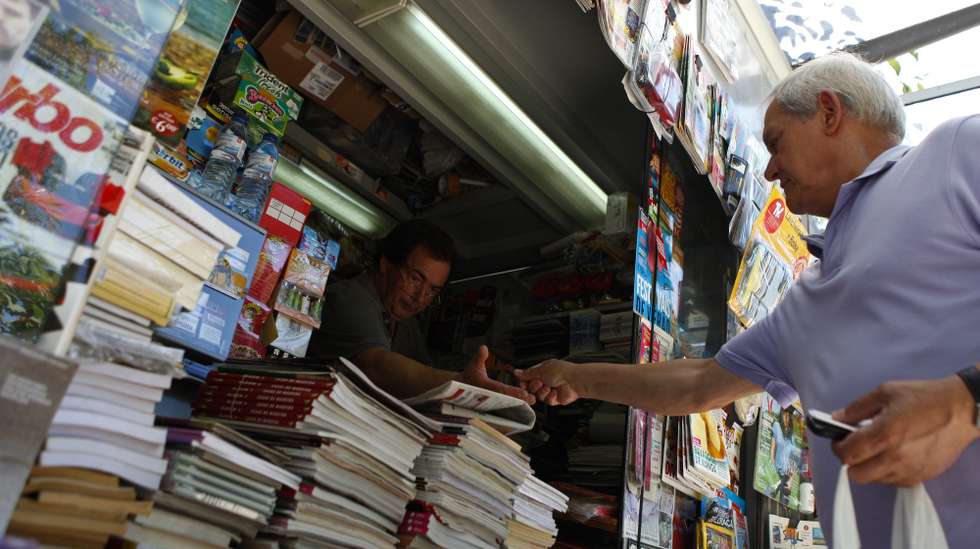 Um popular compra os jornais num quiosque de venda de revistas e jornais, em Lisboa, 13 de julho de 2013. Nos últimos anos, na Avenida da Liberdade, em miradouros pelas sete colinas, nos jardins, à beira Tejo, nas praças, os quiosques foram nascendo ou ganhando vida “como cogumelos” e, reinventando um centenário hábito lisboeta, puseram a cidade a mexer. (ACOMPANHA TEXTO). MIGUEL A. LOPES / LUSA