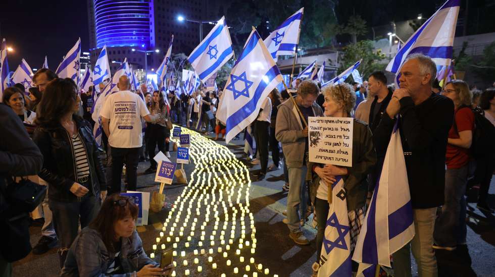 epa10586441 People light candles in memory of fallen Israeli soldiers during a protest against the justice system reform in Tel Aviv, Israel, 22 April 2023. Mass protests continue across the country against the government justice system reform plan.  EPA/ABIR SULTAN