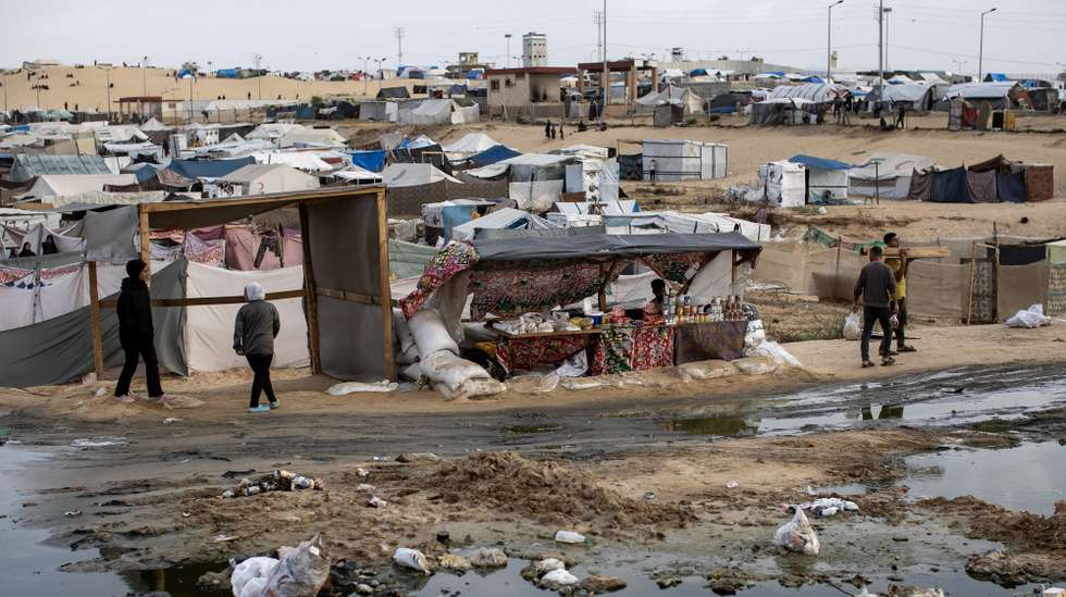 epa11303545 Palestinians walk next to a sewage spill and garbage near tents for internally displaced people at a temporary camp in Rafah camp, southern Gaza Strip, 26 April 2024. Since 07 October 2023, up to 1.7 million people, or more than 75 percent of the population, have been displaced throughout the Gaza Strip, some more than once, in search of safety, according to the United Nations Relief and Works Agency for Palestine Refugees in the Near East (UNRWA), which added that the Palestinian enclave is 'on the brink of famine', with 1.1 million people (half of its population) 'experiencing catastrophic food insecurity' due to the conflict and restrictions on humanitarian access.  EPA/HAITHAM IMAD
