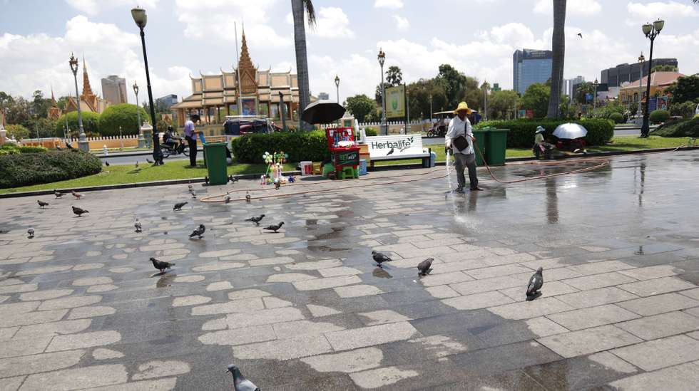 epa11301815 A man sprays water at a park in front of the Royal Palace in Phnom Penh, Cambodia, 26 April 2024. According to the Cambodian Department of Meteorology and Hydrology, temperatures in Cambodia could reach 42 degrees Celsius due to the heatwave.  EPA/KITH SEREY