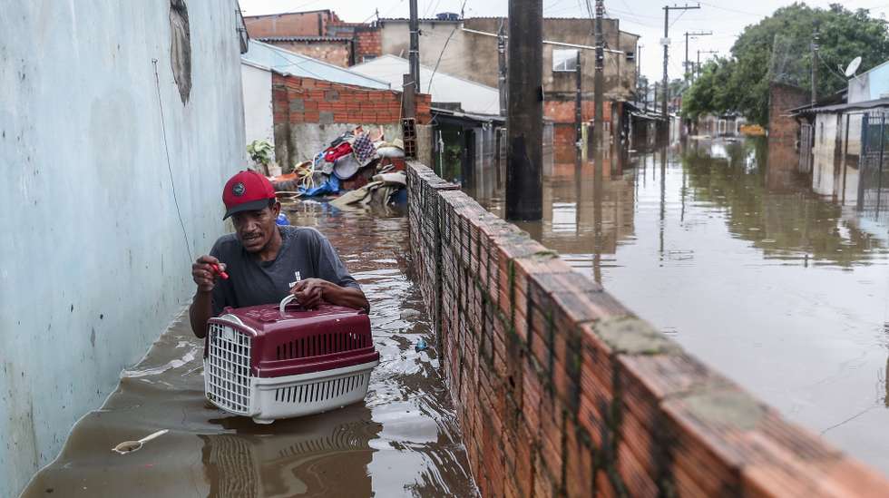 epa11336186 Wagner Souza leaves his flooded house with his cat Lilico in the Humaita neighborhood in Porto Alegre, Brazil, 12 May 2024. Boat rescues in the flooded neighborhoods of Porto Alegre in southern Brazil continue after authorities warned of a new rise in the Guaiba River in the coming days.  EPA/Sebastiao Moreira