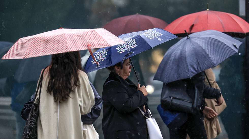 Jovens abrigam-se da chuva com um guarda-chuva junto ao Hospital São João, no Porto, 24 de setembro de 2024. De acordo com o Instituto Português do Mar e da Atmosfera (IPMA), prevê-se a ocorrência de períodos de chuva persistente a partir de hoje nas regiões Norte e Centro e que será por vezes forte na quarta e quinta-feira. ESTELA SILVA/LUSA