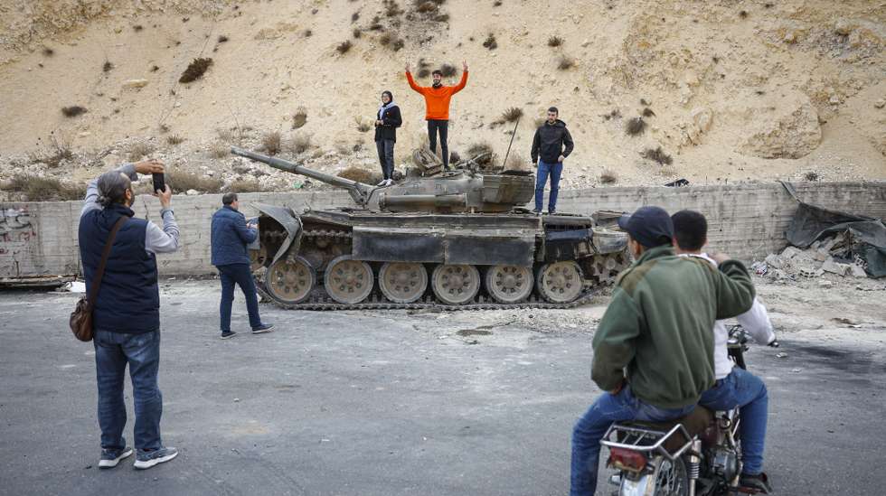 epa11787394 People take pictures of a destroyed military tank in Damascus, Syria, 19 December 2024. Syrian rebels entered Damascus on 08 December 2024 and announced in a televised statement the 'Liberation of the city of Damascus and the overthrow of Bashar al-Assad', as well as the release of all the prisoners.  EPA/ANTONIO PEDRO SANTOS