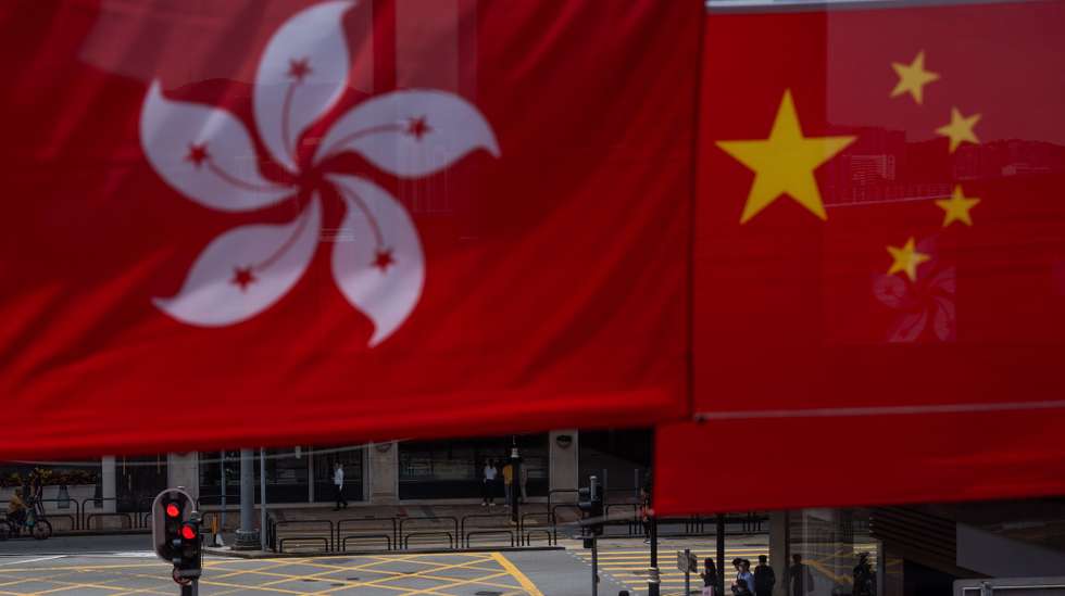 epa10718876 A woman crosses an intersection decorated with Chinese and Hong Kong flags in Hong Kong, China, 30 June 2023. The city will mark the 26th anniversary of the former British colony's return to Chinese rule and the establishment of the Hong Kong Special Administrative Region of the People's Republic of China (Hong Kong SAR or HKSAR) on 01 July 2023.  EPA/BERTHA WANG