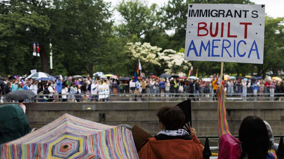 epa12175538 A demonstrator for 'No Kings Day,' holds a sign that reads 'Immigrants Built America,' as they stand along the route of the Boston Pride for the People parade in Boston, Massachusetts, USA, 14 June 2025.  EPA/CJ GUNTHER