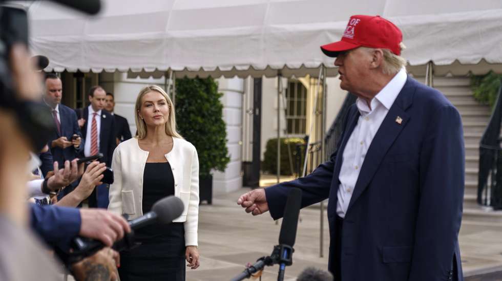 epa12208233 White House Press Secretary Karoline Leavitt (L) listens as US President Donald Trump speaks to the media as he leaves the White House in Washington, DC, USA, 01 July 2025. President Trump is due to visit a new immigration detention facility in the Everglades, Florida.  EPA/WILL OLIVER / POOL