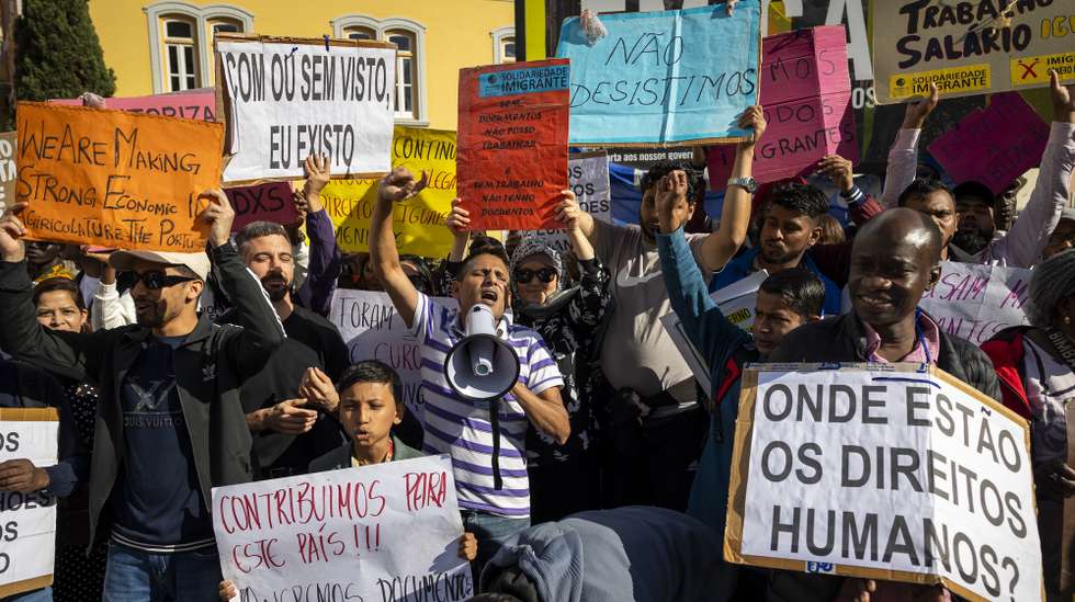Membros de associações de imigrantes gritam palavras de ordem durante uma manifestação para reivindicar a reposição de artigos que permitiam aos imigrantes avançar com um processo de autorização de residência e ficar legalizados, em frente à Assembleia da República, em Lisboa, 25 de outubro de 2024. JOSÉ SENA GOULÃO/LUSA