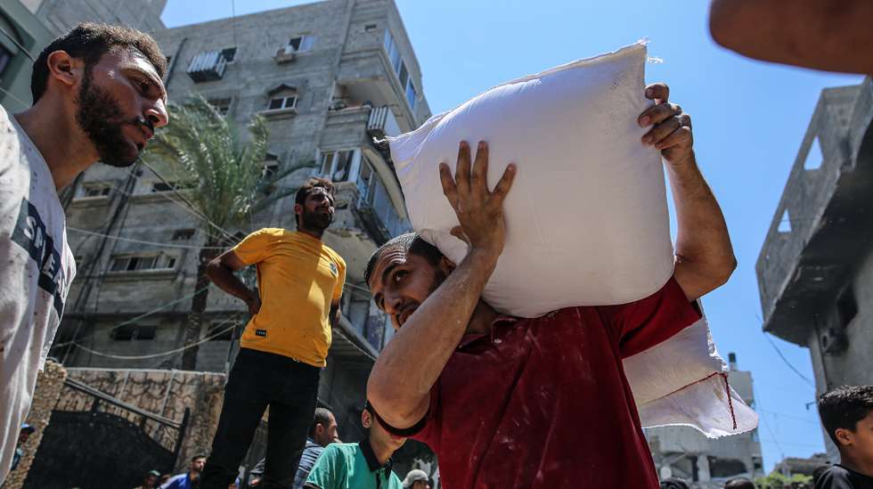 epa12198724 Displaced Palestinians receive aid through the WFP after it successfully arrived at the organization’s warehouses in Gaza City, 26 June 2025. According to the UN half a million people, or one in five people in the Strip are facing starvation while the entire population of the Gaza Strip continues to face a critical risk of famine following 19 months of conflict, mass displacement and severe restrictions on humanitarian aid.  EPA/MOHAMMED SABER