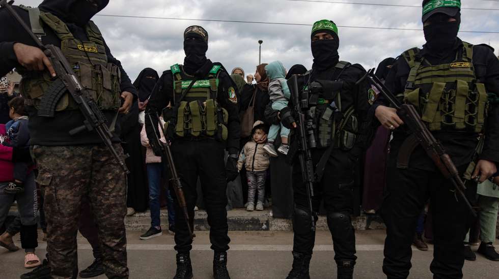 epa11882445 Palestinians with Izz ad-Din al-Qassam fighters after the handing over of three Israeli hostages to the Red Cross as part of a Gaza ceasefire agreement with Israel in Deir al-Balah, central Gaza Strip, 8 February, 2025. In exchange, Israel will release 183 Palestinian prisoners and detainees.  EPA/HAITHAM IMAD