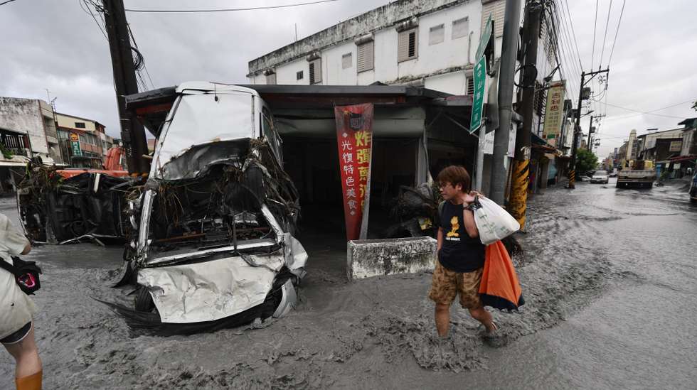 epaselect epa12401219 A man walks past a damaged vehicle on a flooded street in the aftermath of Super Typhoon Ragasa in Guangfu Township, Hualien County, Taiwan, 24 September 2025. At least 14 people have died, 32 were injured and more than 150 are missing in the eastern county after a barrier lake in the mountains overflowed and inundated the township during the typhoon, according to the Ministry of Health and Welfare.  EPA/RITCHIE B. TONGO