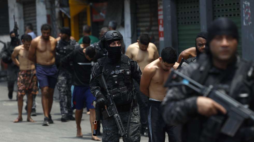 epa12487894 Rio de Janeiro Police officers guard a group of people during an operation in Rio de Janeiro, Brazil, 28 October 2025. At least twenty people were killed and fifty were arrested during a major police operation against Comando Vermelho, one of the most powerful organized crime gangs in Rio de Janeiro.  EPA/ANTONIO LACERDA