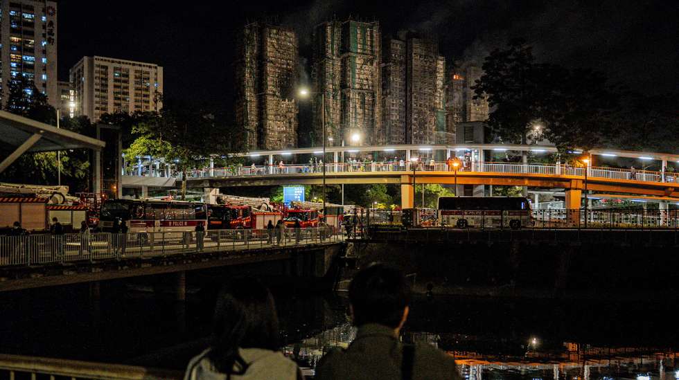 epa12552596 Passersby look on the damage in the buildings following the Tai Po fire in Hong Kong, China, 27 November 2025. The fire, which started on 26 November, has killed at least 65 people, and left hundreds missing.  EPA/LEUNG MAN HEI