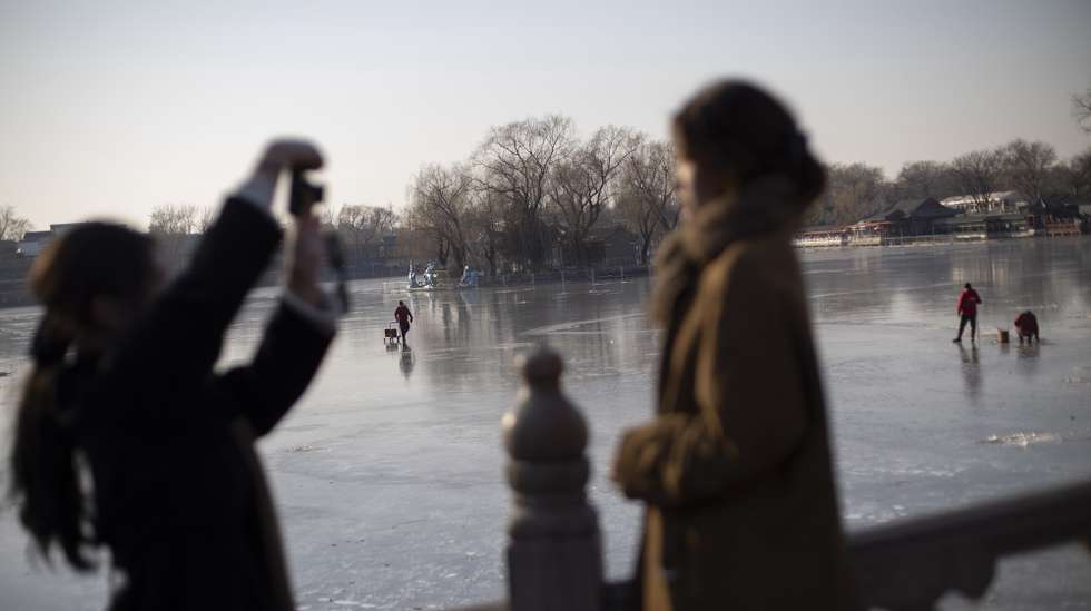 epa12621500 People pose for pictures near the Qianhai Lake as city personnel works in the background, in Beijing, China, 02 January, 2026.  EPA/ANDRES MARTINEZ CASARES