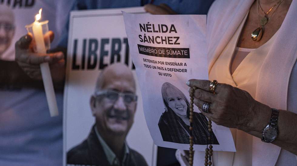 epa12654757 People hold signs during a day of prayer in Maracaibo, Venezuela, 16 January 2026. Student leaders from the University of Zulia called for the release of political prisoners, including two professors from the institution.  EPA/Henry Chirinos