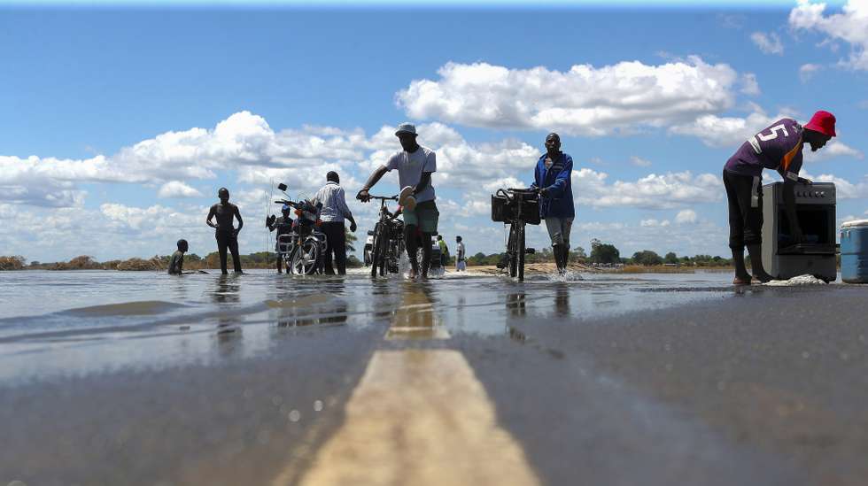 Populares atravessam estrada submersa devido às cheias em Chókwe, na província de Gaza, Moçambique, 03 de fevereiro de 2026. As cheias que afetam Moçambique há quase um mês atingiram particularmente Chókwè, no sul, considerado o celeiro do país, com o vale do Limpopo a ocupar em pouco dias 88% do território, engolindo meses de produção agrícola, nomeadamente arroz, além de centenas de casas inundadas e destruídas. (ACOMPANHA TEXTO DA LUSA DO DIA 07 DE FEVEREIRO DE 2026). LUÍSA NHANTUMBO/LUSA