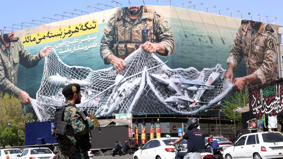 epa12870206 A member of the Iranian security forces watches over traffic passing a huge political billboard reading in Persian ’The Strait of Hormuz will remain closed', in Enghelb square in Tehran, Iran, 05 April 2026. Iran's Revolutionary Guards (IRGC) said a US aircraft that had been searching for the crew member of a missing US fighter jet had been destroyed, Iranian media reported on 05 April 2026.  EPA/ABEDIN TAHERKENAREH