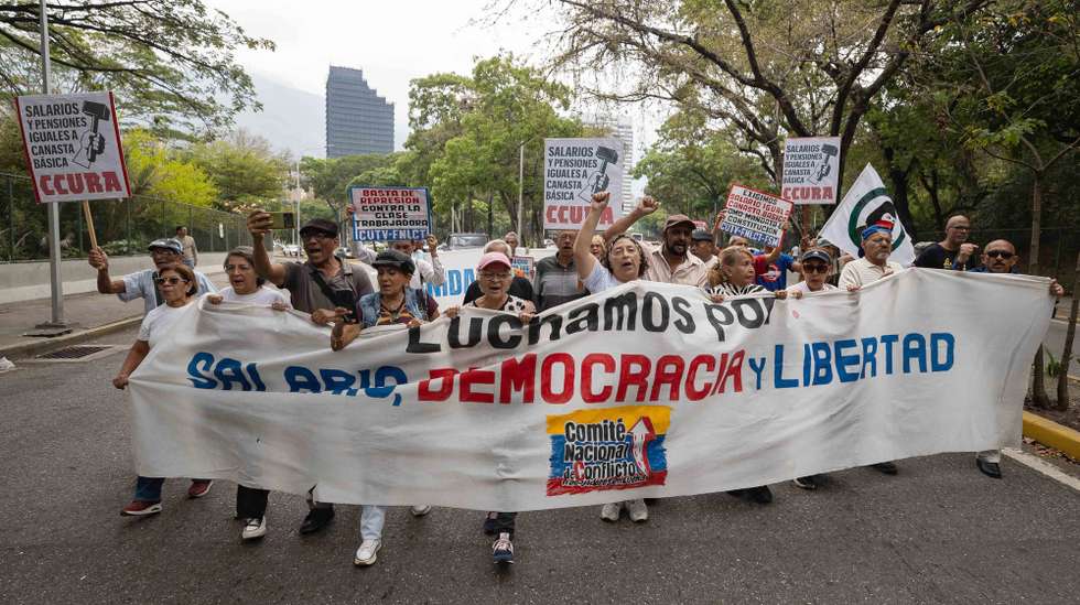 epa12907835 People hold a banner during a strike by university educators outside the Central University of Venezuela in Caracas, Venezuela, 22 April 2026. Workers at 23 public universities began a 24-hour strike to demand an increase in the minimum wage, which has remained the same since 2022 and is equivalent to 0.27 US dollars per month under the official exchange rate.  EPA/RONALD PENA R