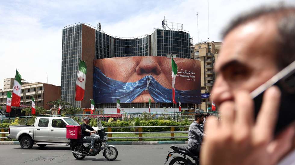 epa12935915 People drive near a huge anti-US billboard with photo depicting US President Donald Trump at Valiasr square in Tehran, Iran, 06 May 2026. US President Donald Trump announced pausing the operation of escorting ships through the Strait of Hormuz, hinting at progress in peace talks with Tehran.  EPA/ABEDIN TAHERKENAREH