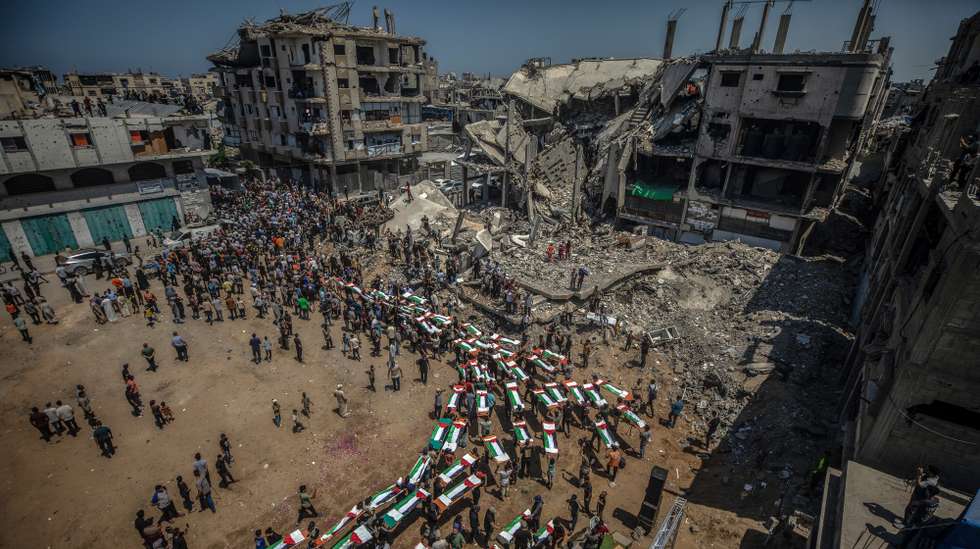 epa13149753 Palestinians gather during a mass funeral for 112 members of the Abu Sharia and Al-Hasayna families in the eastern Gaza City, 04 August 2026. Gaza's Civil Defense recovered the remains during two weeks of searching through the rubble of residential buildings destroyed during an Israeli airstrike in November 2023. According to the Civil Defense, the victims, including women and children, were killed on 22 November 2023 and remained trapped beneath the debris for nearly three years before being recovered and laid to rest.  EPA/MOHAMMED SABER
