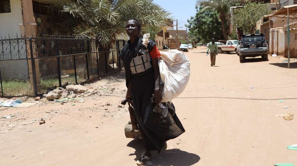 epa10579958 A Sudanese woman carries her belongings on a street in Khartoum, Sudan, 19 April 2023. A power struggle erupted since 15 April between the Sudanese army led by army Chief General Abdel Fattah al-Burhan and the paramilitaries of the Rapid Support Forces (RSF) led by General Mohamed Hamdan Dagalo, resulting in at least 200 deaths according to doctors' association in Sudan.  EPA/STRINGER