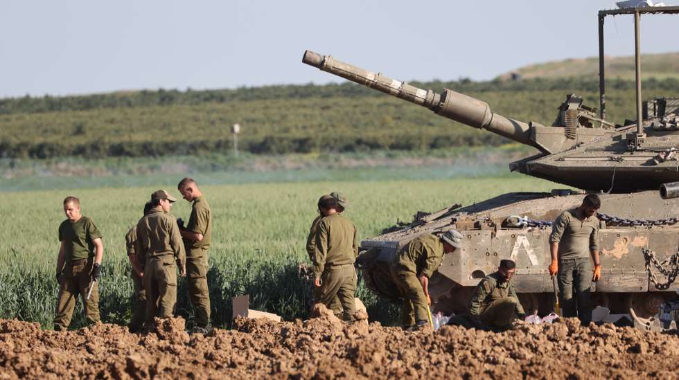 epa11211358 Israeli soldiers stand next to a tank near the border fence with the Gaza Strip, as seen from the Israeli side in southern Israel, 10 March 2024. More than 31,000 Palestinians and over 1,300 Israelis have been killed, according to the Palestinian Health Ministry and the Israel Defense Forces (IDF), since Hamas militants launched an attack against Israel from the Gaza Strip on 07 October 2023, and the Israeli operations in Gaza and the West Bank which followed it.  EPA/ABIR SULTAN
