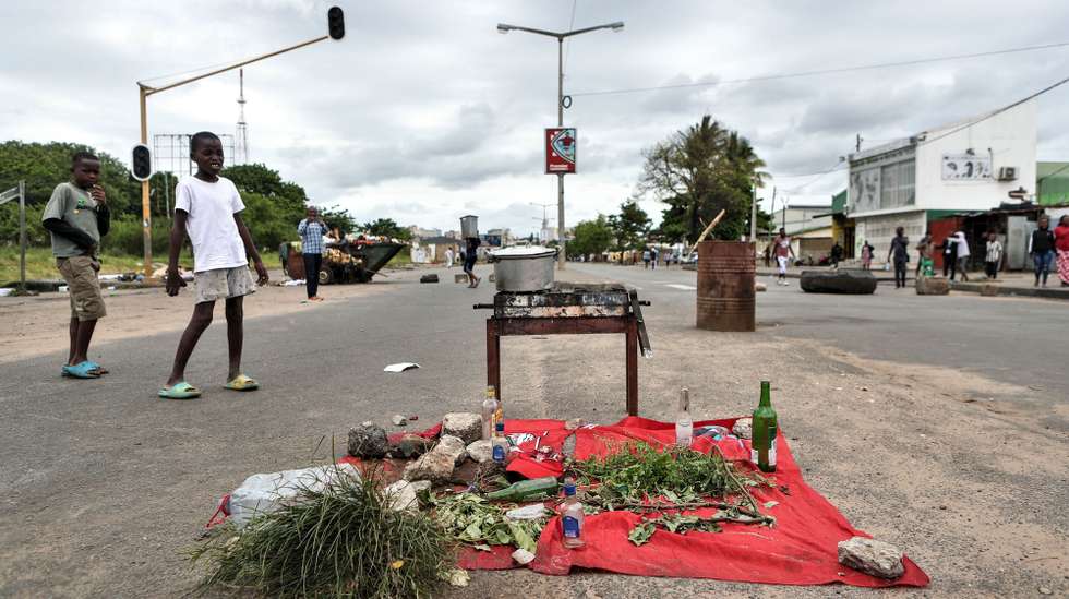 Crianças observam um fogao improvisado numa estrada bloqueada em Maputo, Moçambique, 28 de novembro de 2024. Barricadas tomaram conta hoje de Maputo, com ruas e avenidas centrais praticamente sem viaturas, ocupadas por manifestantes, pedras, contentores do lixo, ferros, paus e tudo o que permita bloquear a passagem, em mais uma ação de protesto pós-eleitoral. LUISA NHANTUMBO/LUSA