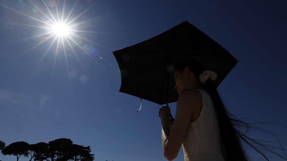 epa13080730 A woman shelters from the sun under an umbrella at Cap d'Antibes, southern France, 02 July 2026. Temperatures in Antibes reached up to 37 degrees Celcius as a spell of hot weather affected much of Europe.  EPA/SEBASTIEN NOGIER
