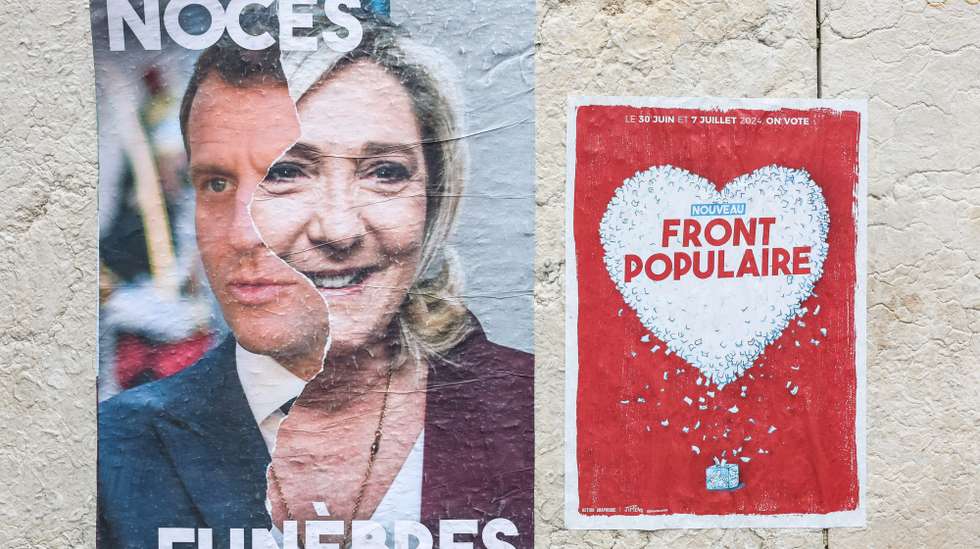 epa11455806 A poster with a photograph of French President Emmanuel Macron (L) and French member of Parliament for far-right Rassemblement National (RN) party Marine Le Pen (2-L), reads 'funeral wedding', next to a sticker for 'New Popular Front', pictured during a rally called by French unions and civil society organisation against far right party RN, ahead of second round of elections, in Paris, France, 03 July 2024. A protest was organised, on 03 July, by some of the French independent media as well as labour unions and civil society organisations, to call for a 'Democratic Front against far right' in Place de la Republique in Paris, as France's far right National Rally has made significant gains in the first round of parliamentary elections one week earlier. The second round of the elections for a new Parliament is to be held on 07 July 2024.  EPA/MOHAMMED BADRA