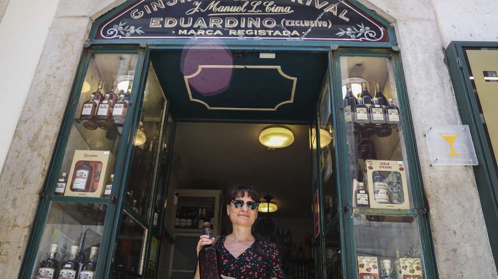 Uma turista turca posa para a fotografia com uma garrafa de ginjinha na porta de entrada da histórica loja "Ginjinha sem Rival", nas Portas de Santo Antão, em Lisboa, 25 de junho de 2025. A histórica loja Ginjinha Sem Rival, instalada na zona histórica de Lisboa desde 1890, tem ordem para encerrar portas já no final deste mês, mas o gerente promete “lutar até ao fim”, nem que seja nos tribunais. (ACOMPANHA TEXTO DA LUSA DA LUSA DO DIA 27 DE JUNHO DE 2025). TIAGO PETINGA/LUSA