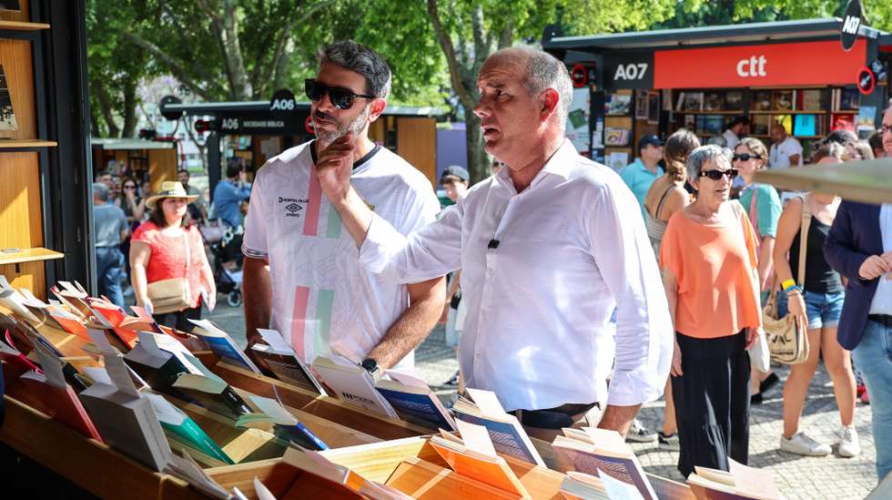 O secretário-geral do Partido Comunista  Português (PCP), Paulo Raimundo (D), conversa com uma vendedora durante uma visita à 95ª edição da Feira do Livro, no Parque Eduardo VII, em Lisboa, 19 de junho de 2025. ANTÓNIO COTRIM/LUSA