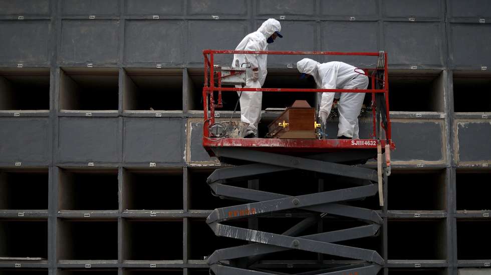 epa09039251 Health personnel carry out the burial of a coronavirus victim at Sao Franscisco Xavier cemetery in Rio de Janeiro, Brazil, 26 February 2021. Brazil, one of the countries hardest hit by the pandemic in the world, added 1,337 new deaths from COVID in the last 24 hours, bringing the average number of deaths in the last 14 days to 1,100 a day, the highest level since the record of the first case of the disease, exactly one year ago.  EPA/FABIO MOTTA