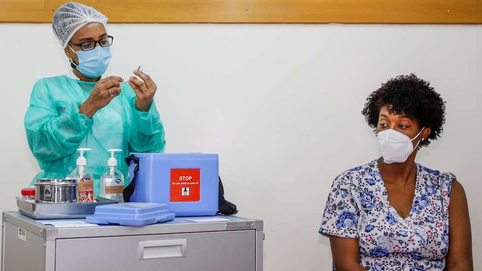 Uma profissional de saúde administra a vacina da Pfizer a covid-19 a um dos seis profissionais de saúde da Praia, antecedendo o início da campanha de vacinação em Cabo Verde, sexta-feira, precisamente um ano depois da chegada da pandemia ao arquipélago, no Centro de Saúde da Achada de Santo António, na Praia, Cabo Verde, 18 de março de 2021. FERNANDO DE PINA/LUSA