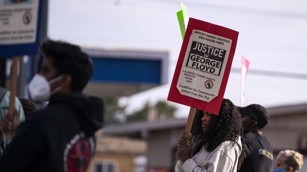 epa09131822 A protester holds a poster reading 'Justice for George Floyd' during a demonstration against police violence and in reaction to the officer-involved deaths of George Floyd and Daunte Wright deaths, in Los Angeles, California, USA, 12 April 2021.  EPA/ETIENNE LAURENT