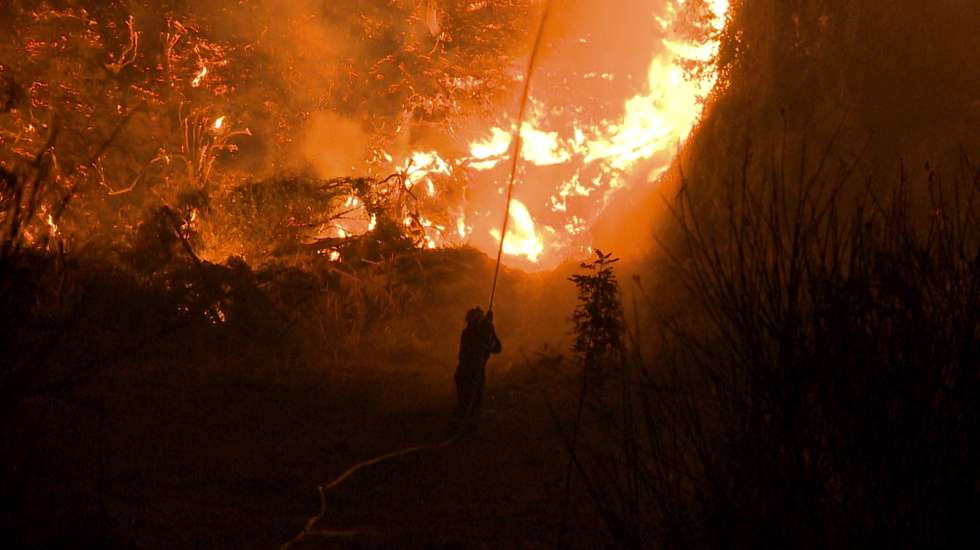 epa09409419 A firefighter sprays water during a wildfire in a forest area near the village of Kamatriades in Evia, on the night of 110 August 2021 (issued on 11 August 2021). Fires that broke out in Attica and Evia island this week have burned more than a quarter of a million stremmas, the National Observatory of Athens' center Beyond said on 08 August. Some 76,150 stremmas (7,615 hectares) have been burnt so far in northern Attica. In Evia island the surface area of burnt land is measured at 197,940 stremmas (19,794 hectares). These figures concern only the fires in Attica and Evia, but dozens of large fires have affected several areas across the country.  EPA/SPIROS KOUROS