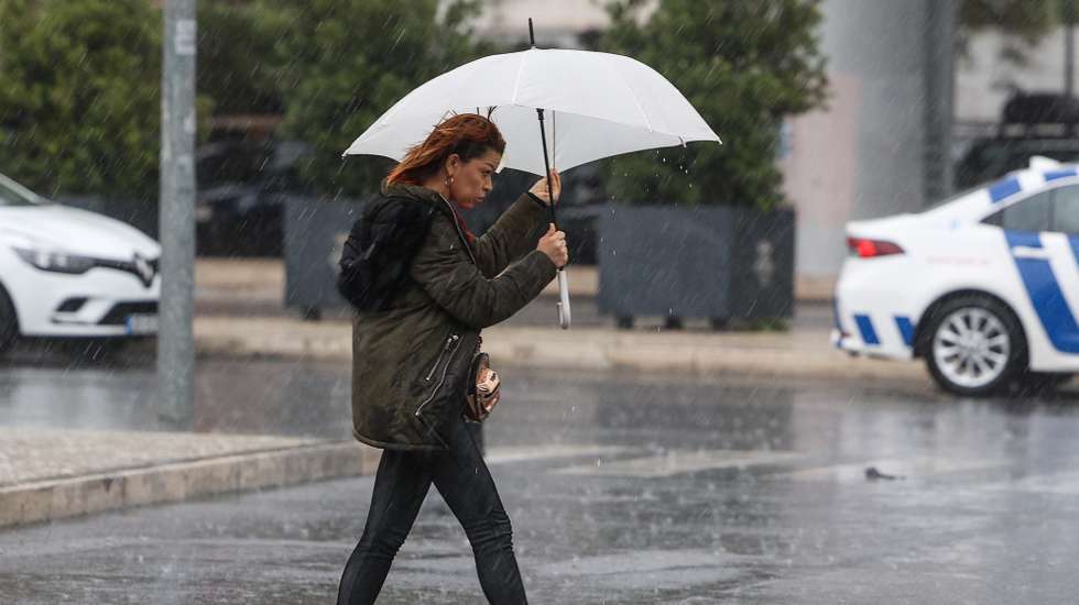 Uma traseunte passa com chapéu de chuva na zona de Algés em Oeiras num dia de temporal, 14 de dezembro de 2022. TIAGO PETINGA/LUSA